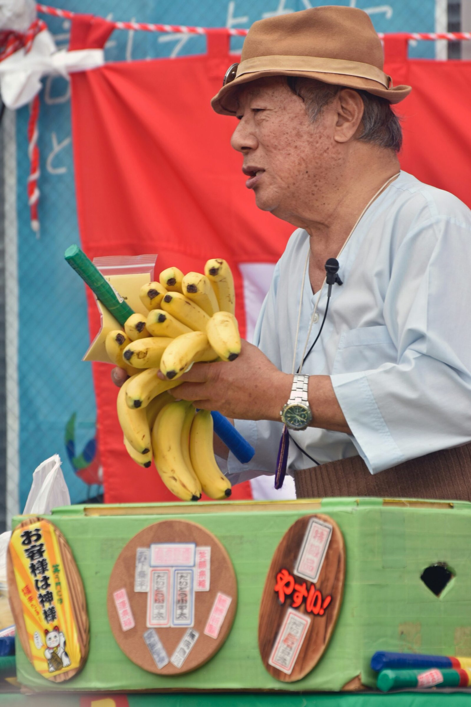 A man holding a bunch of bananas on top of a table